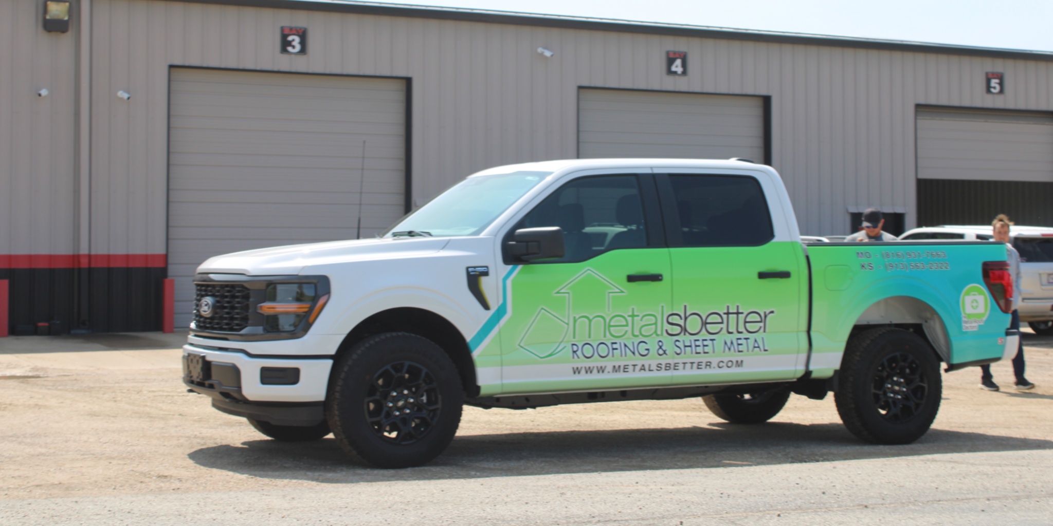 Custom vinyl vehicle wrap on a white pickup truck featuring green branding graphics for a roofing and sheet metal company parked outside a commercial building in Missouri.